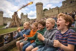 excited childern at castle watching a trebuchet display
